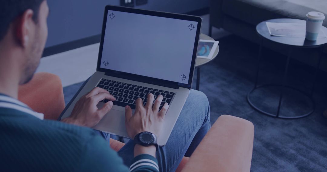 Man typing on laptop in cozy lounge with blank screen and copy space for remote work