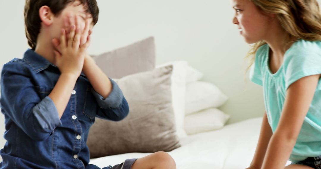 Upset Boy Covering Face While Girl Stares on Bed - Free Images, Stock Photos and Pictures on Pikwizard.com