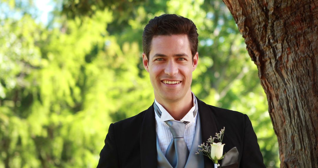 Groom Standing by Tree Smiling at Camera on Sunny Wedding Day - Free Images, Stock Photos and Pictures on Pikwizard.com