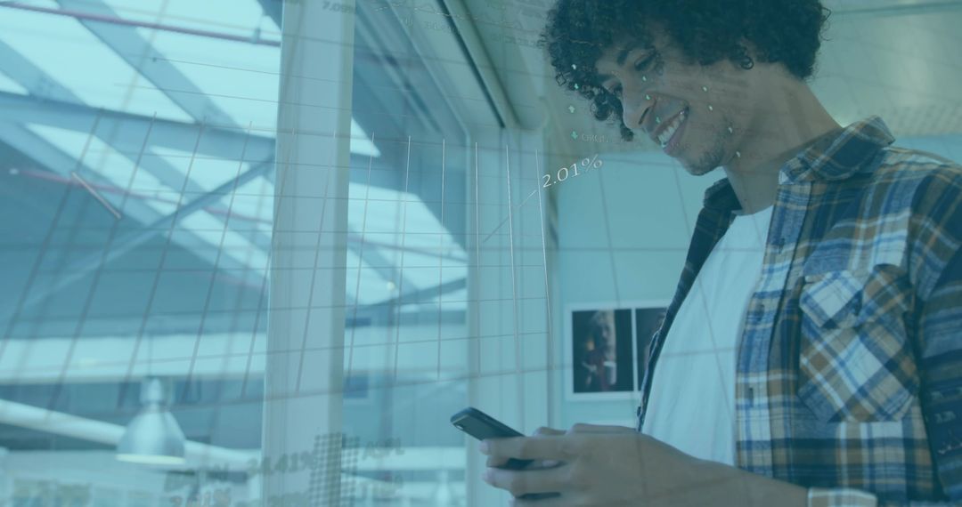 Smiling young man checking smartphone in modern glass atrium with data graphs overlay