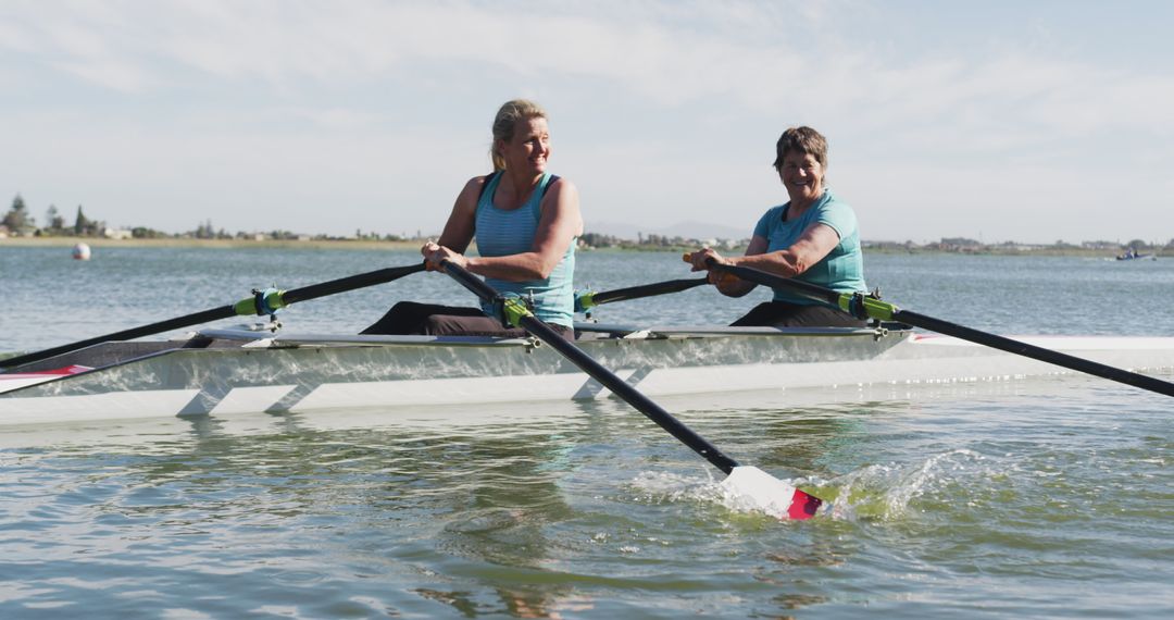 Two Women Rowing in Synch on Calm Lake on a Sunny Day - Free Images, Stock Photos and Pictures on Pikwizard.com