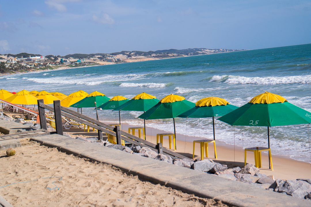 Green and Yellow Parasols on Sandy Beach by Blue Ocean Waves - Free Images, Stock Photos and Pictures on Pikwizard.com