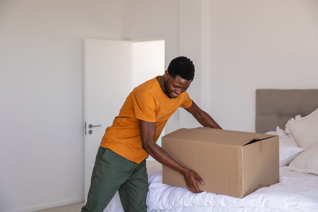 Man Handling Cardboard Box in Bright Minimalistic Bedroom