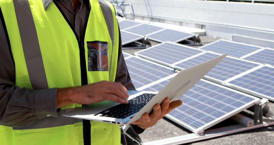 Engineer in Safety Vest Using Laptop near Solar Panels - Free Images, Stock Photos and Pictures on Pikwizard.com