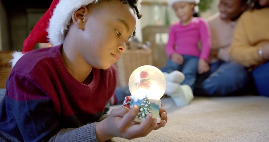 Curious Child With Snow Globe During Christmas Family Time - Free Images, Stock Photos and Pictures on Pikwizard.com