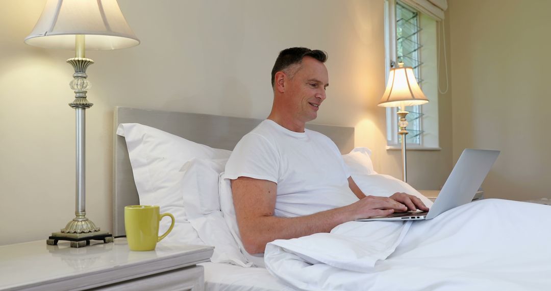 Man Working Comfortably from Bed with Laptop in Cozy Bedroom - Free Images, Stock Photos and Pictures on Pikwizard.com