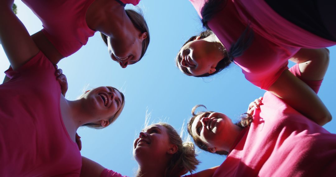 Team of Smiling Women in Pink Forming Circle Against Blue Sky - Free Images, Stock Photos and Pictures on Pikwizard.com