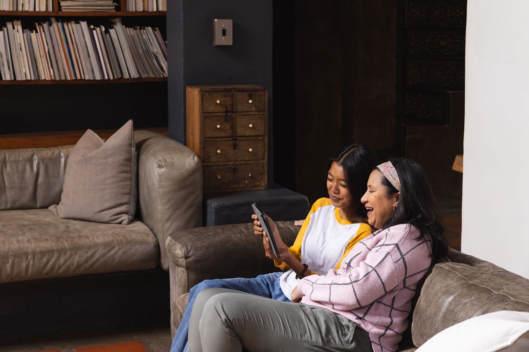 Mother and Daughter Relaxing with Digital Tablet at Home