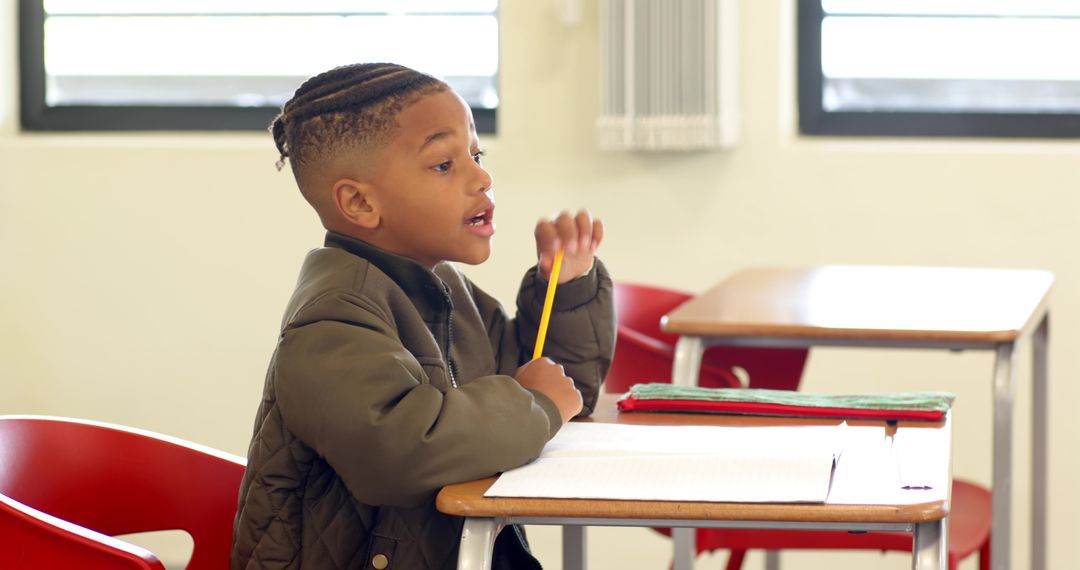 Focused Boy Writing in Classroom with Notebook