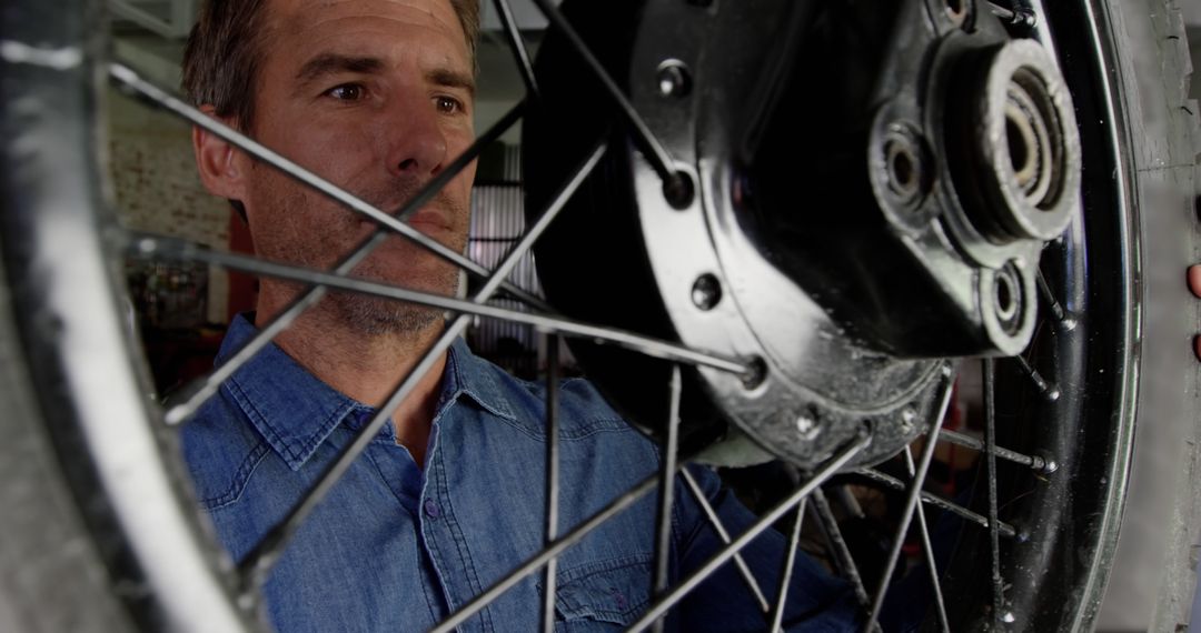 Mechanic Inspecting Motorcycle Wheel in Garage - Free Images, Stock Photos and Pictures on Pikwizard.com