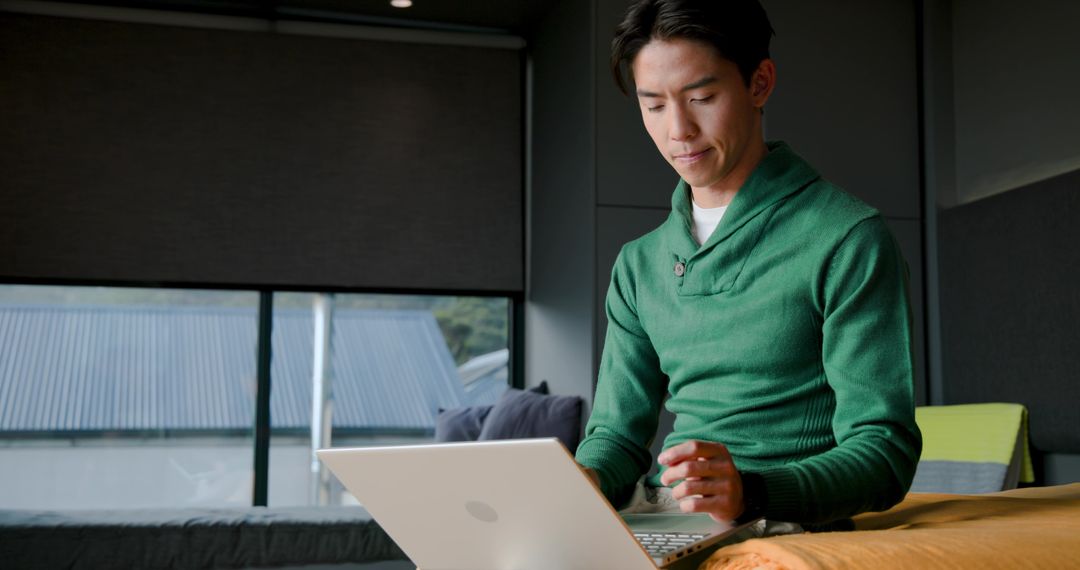 Concentrated Man Typing on Laptop in Modern Home Environment