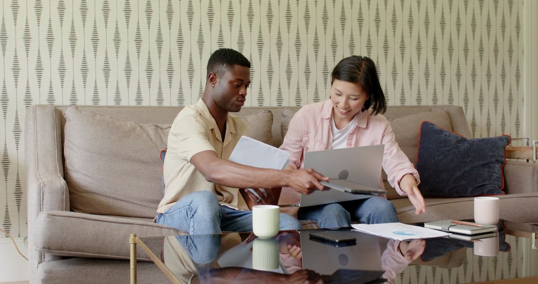 Diverse Team Collaborating on Laptop and Documents in Casual Workspace
