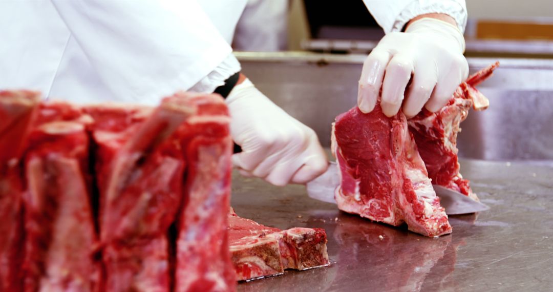 Butcher cutting raw meat with knife on stainless steel table - Free Images, Stock Photos and Pictures on Pikwizard.com