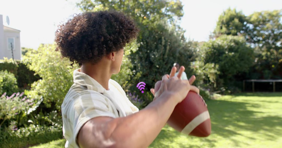 Young man preparing to throw football in sunny backyard with Wi Fi signal overlay