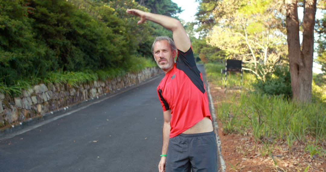 Middle-aged man stretching outdoors in casual athletic wear - Free Images, Stock Photos and Pictures on Pikwizard.com