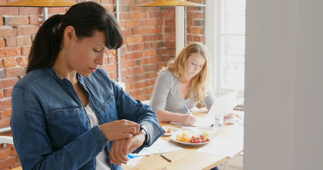 Two Women Working in a Modern Office Space with Brick Wall and Natural Light - Free Images, Stock Photos and Pictures on Pikwizard.com