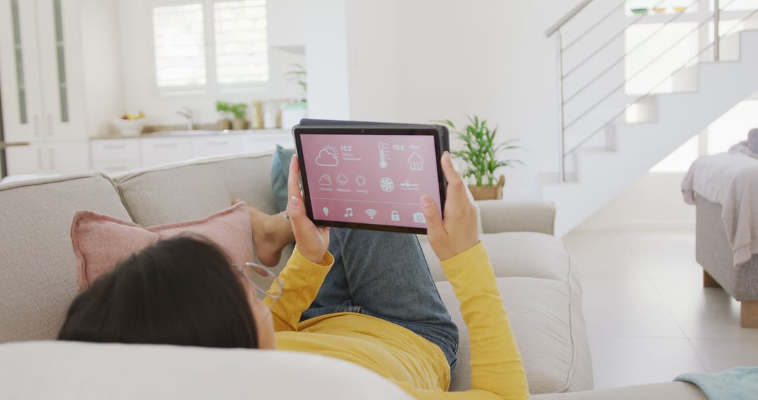 Relaxed Asian Woman Using Tablet on Couch in Sunny Living Room - Free Images, Stock Photos and Pictures on Pikwizard.com