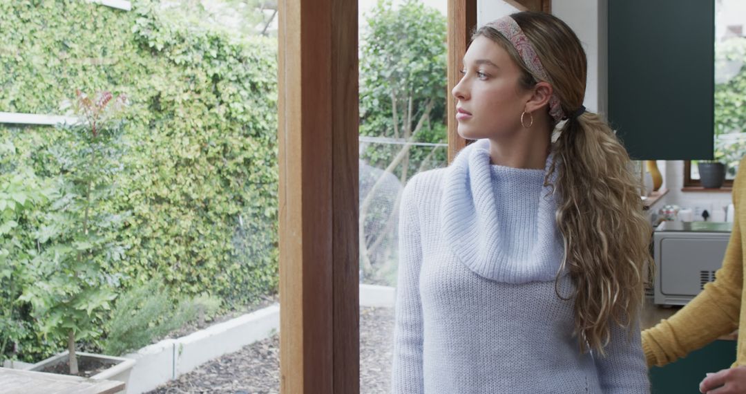 Young Woman Gazing Out Window in Cozy Home Setting - Free Images, Stock Photos and Pictures on Pikwizard.com