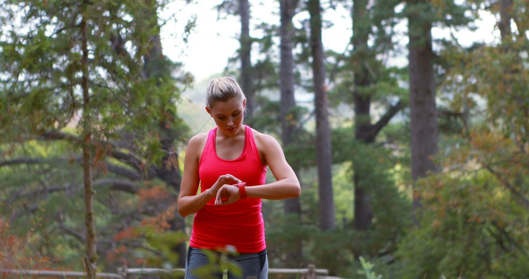 Woman Checking Smartwatch While Exercising in Forest - Free Images, Stock Photos and Pictures on Pikwizard.com