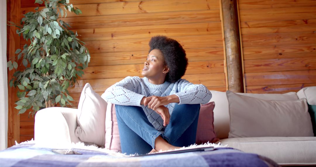 Thoughtful Young Woman Relaxing on Cozy Sofa in Wooden Cabin - Free Images, Stock Photos and Pictures on Pikwizard.com