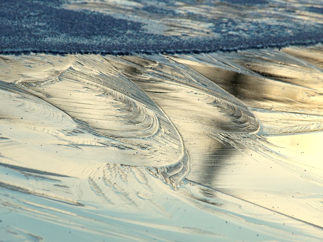 Golden Wet Sand Swirls and Tide Ripples Reflecting Sunset Light
