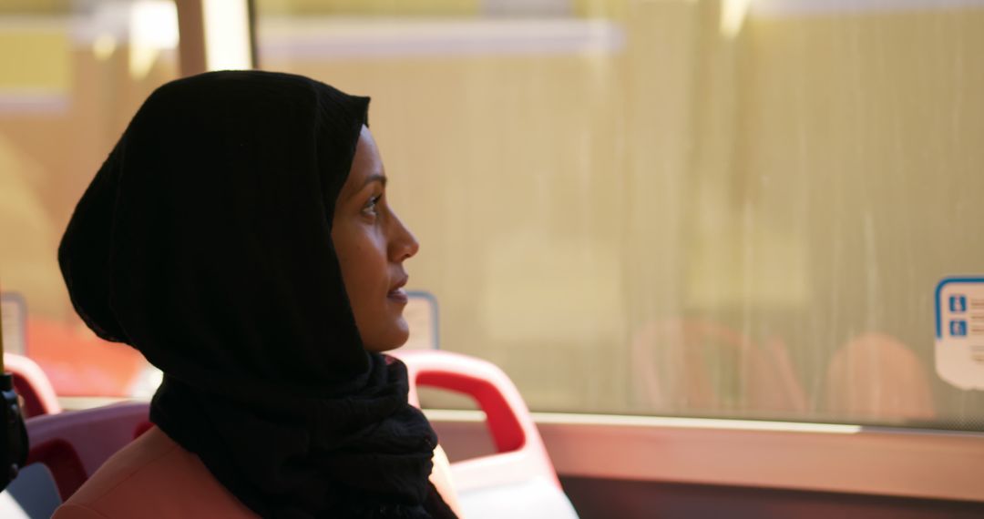 Thoughtful Woman in Hijab Reflecting During Bus Ride - Free Images, Stock Photos and Pictures on Pikwizard.com