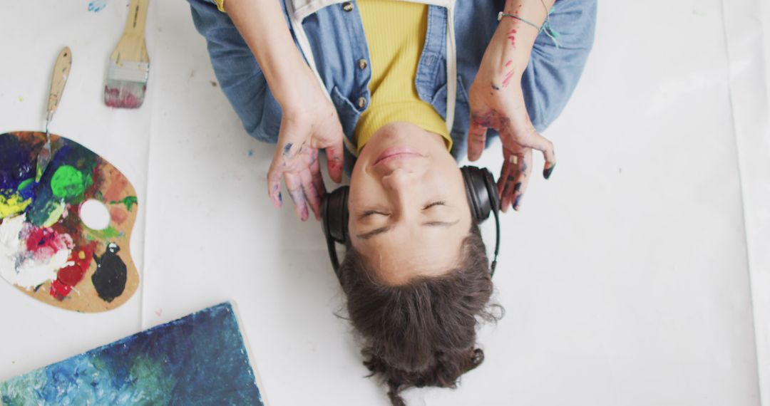 Artist Listening to Music While Lying on Floor with Paint Supplies Around - Free Images, Stock Photos and Pictures on Pikwizard.com