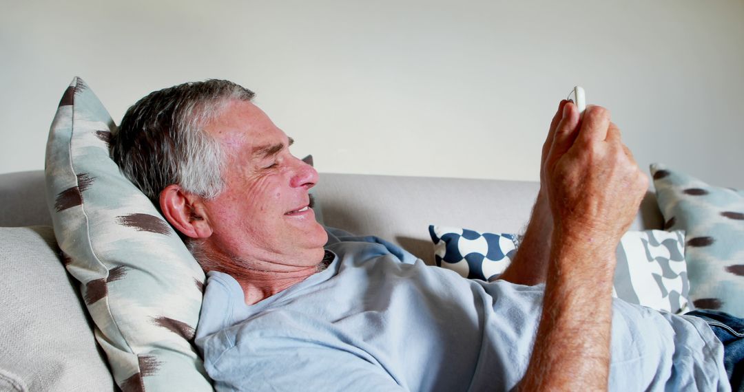 Smiling Senior Man Relaxing on Sofa Using Smartphone - Free Images, Stock Photos and Pictures on Pikwizard.com