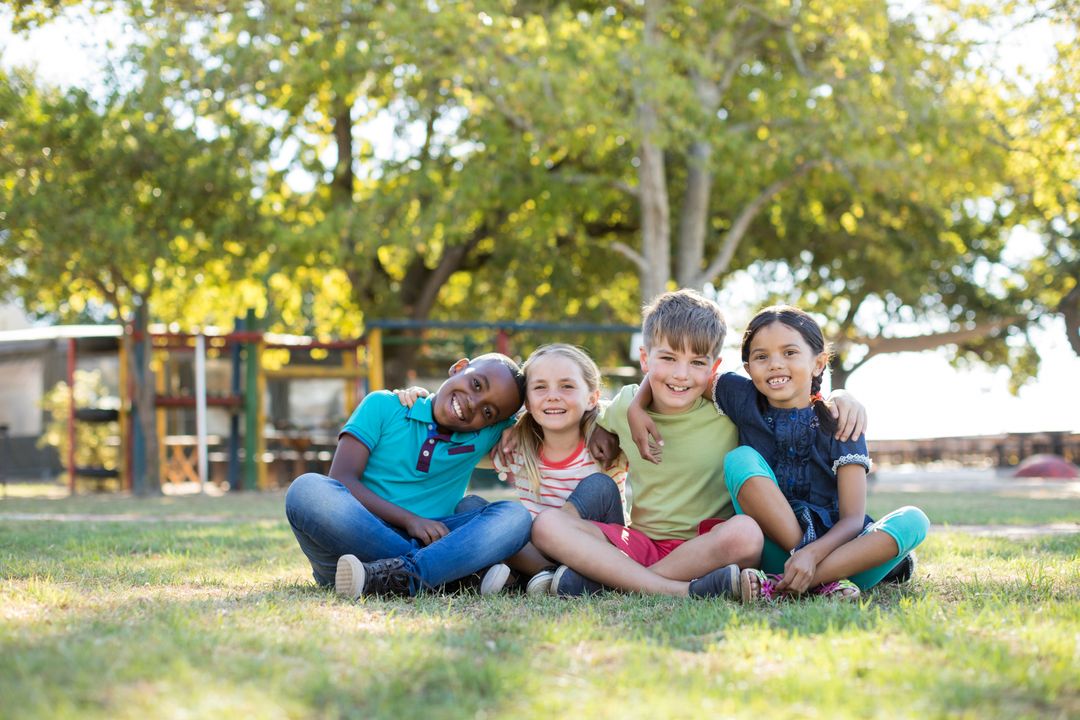 Happy Children Sitting on Grassy Field in Park - Free Images, Stock Photos and Pictures on Pikwizard.com