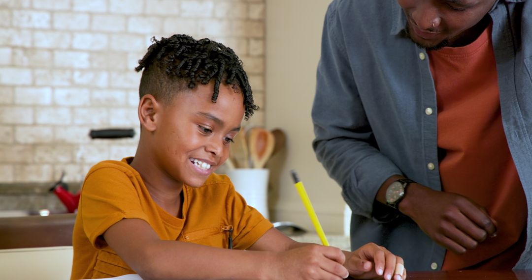 Father Helping Smiling Son with Homework at Home Table