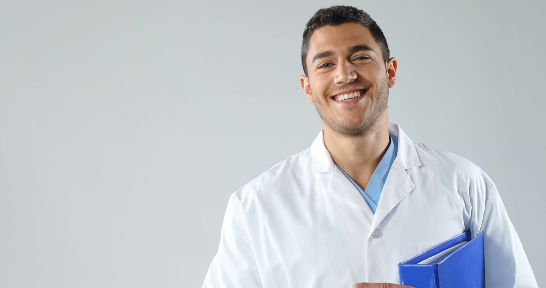 Smiling Young Doctor Holding Medical File in Hospital - Free Images, Stock Photos and Pictures on Pikwizard.com