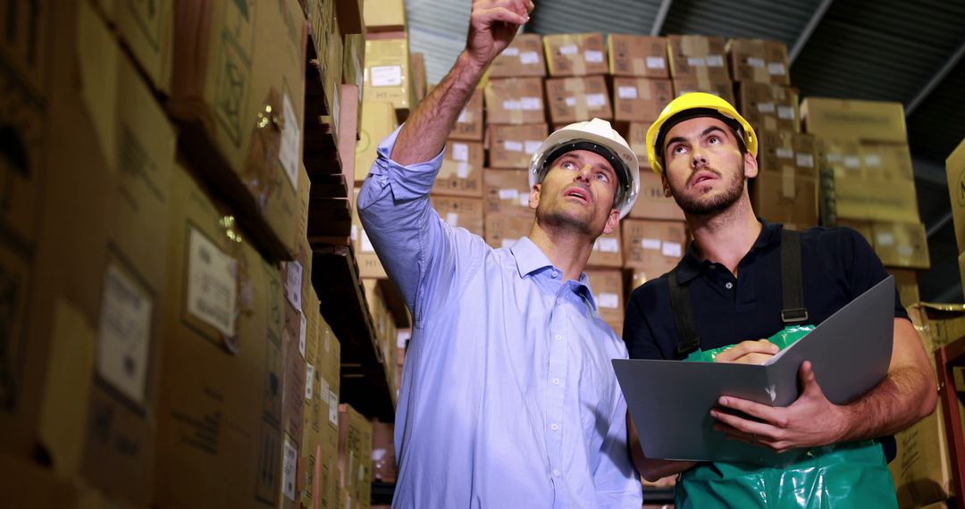 Warehouse Workers Discussing Inventory Management Among Stacks of Boxes - Free Images, Stock Photos and Pictures on Pikwizard.com