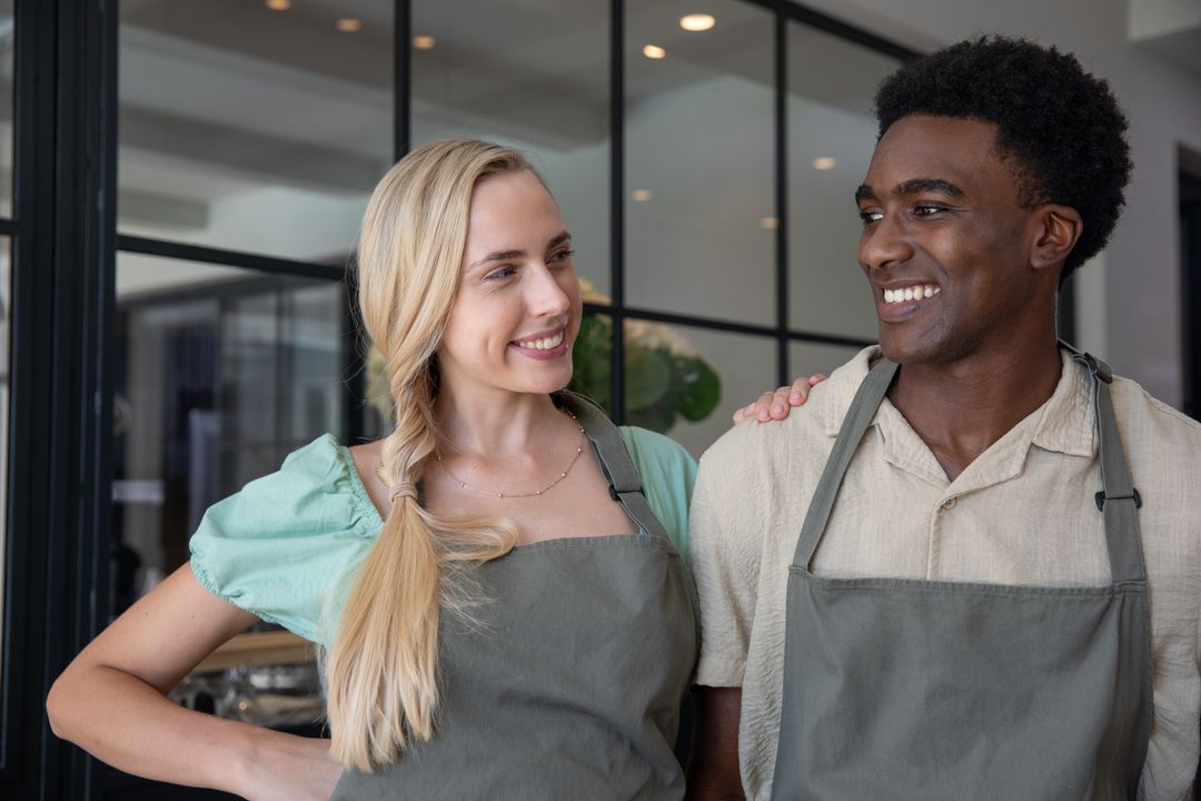 Diverse Coworkers Wearing Aprons Smiling in Modern Cafe