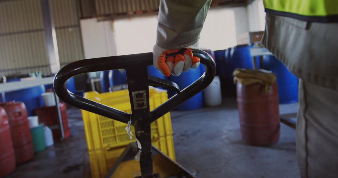 Worker Gripping Pallet Jack Handle in Industrial Warehouse with Yellow Crate and Safety Vest