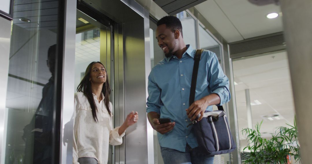 Image of happy diverse woman and man walking outside elevator and talking - Free Images, Stock Photos and Pictures on Pikwizard.com