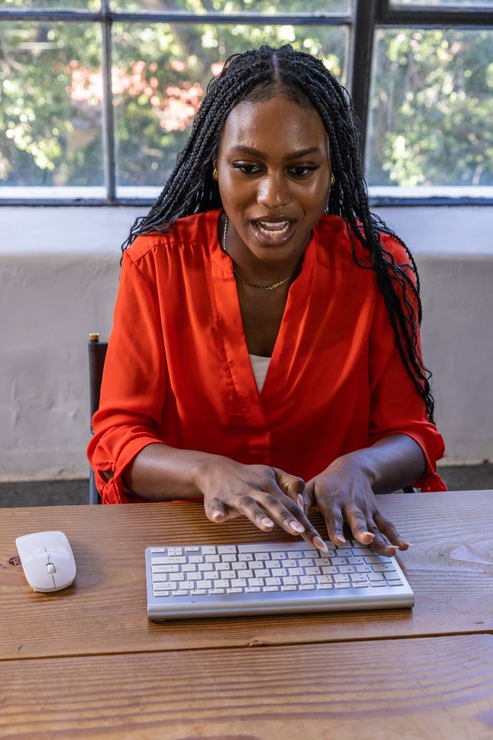 Professional Woman Typing on Wireless Keyboard by Window