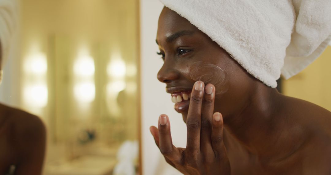 Smiling Woman in Towel Applying Face Cream in Bathroom - Free Images, Stock Photos and Pictures on Pikwizard.com