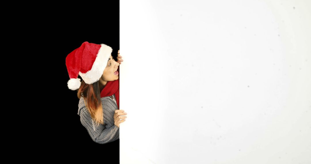 Woman in Santa Hat Peeking Behind Blank Panel - Free Images, Stock Photos and Pictures on Pikwizard.com
