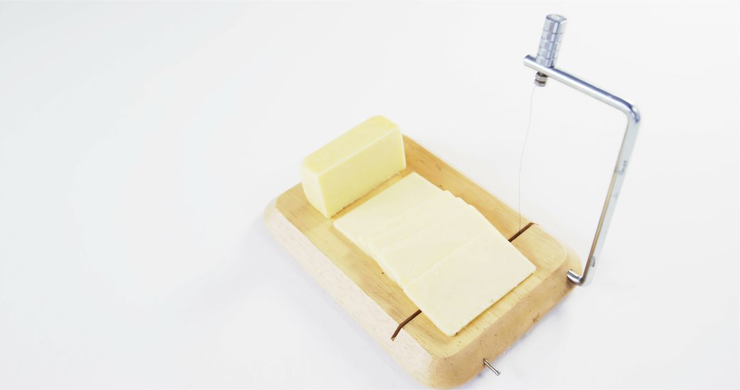 A block of butter is being sliced with a metal wire cutter on a wooden board, with copy space - Free Images, Stock Photos and Pictures on Pikwizard.com
