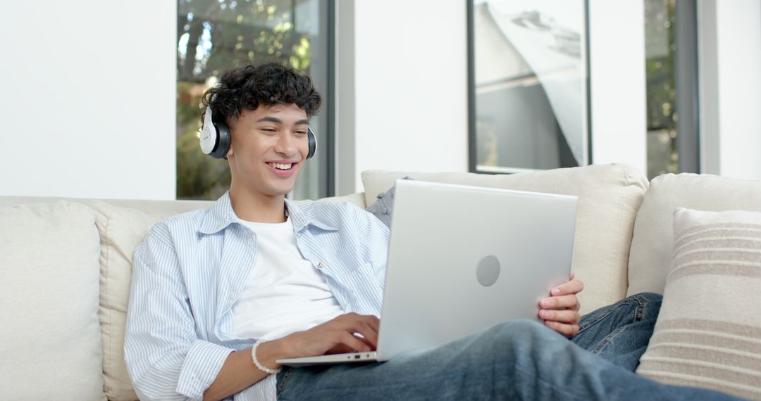 Young Man Enjoying Music While Using Laptop at Home