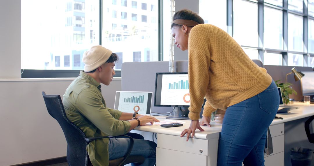 Diverse coworkers collaborating on data charts at modern open-plan office desk