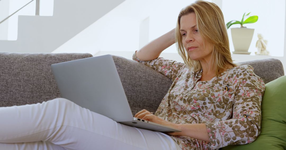 Middle-Aged Woman Relaxing on Couch Using Laptop in Modern Home - Free Images, Stock Photos and Pictures on Pikwizard.com