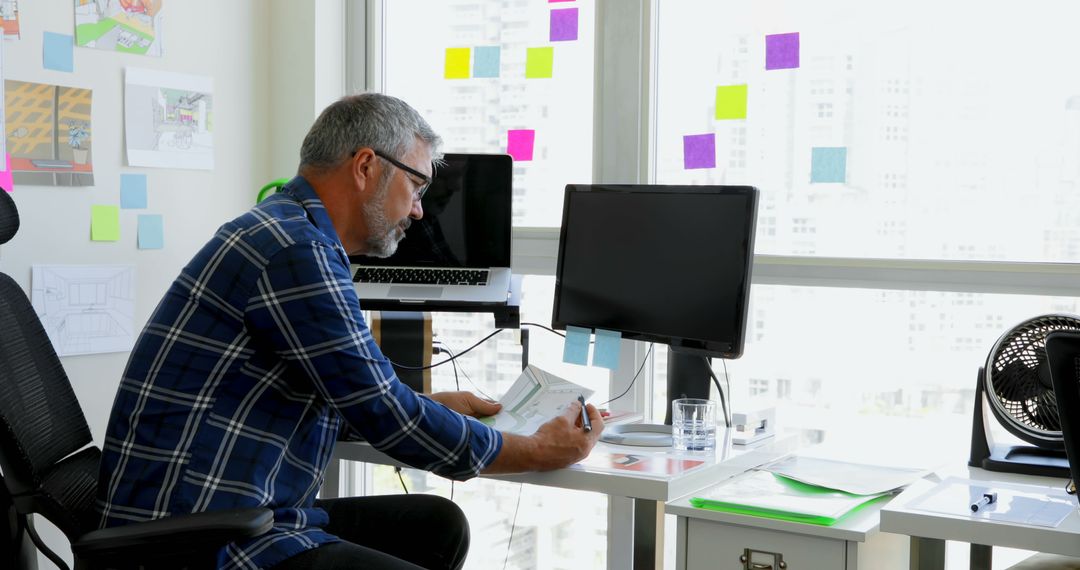 Middle-aged Man Working in Modern Home Office with Sticky Notes on Window - Free Images, Stock Photos and Pictures on Pikwizard.com