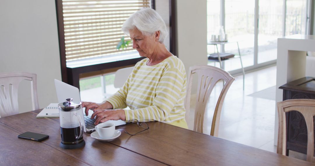 Senior woman working on laptop at home with coffee - Free Images, Stock Photos and Pictures on Pikwizard.com