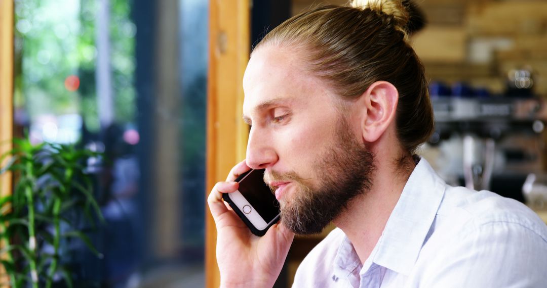 Young Man with Beard Talking on Smartphone in Coffee Shop - Free Images, Stock Photos and Pictures on Pikwizard.com