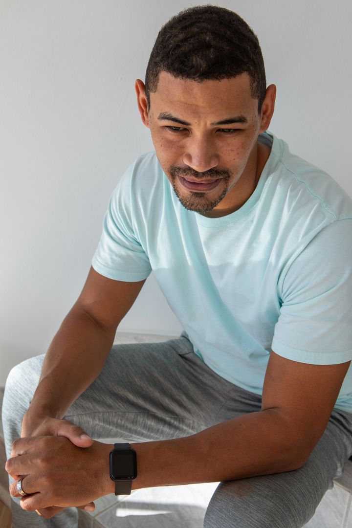 Man in Turquoise Tee Displaying Smartwatch with Relaxed Expression