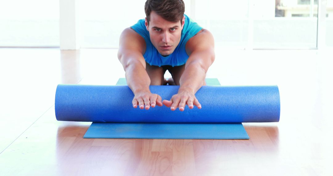 Man Stretching on Yoga Mat with Foam Roller in Bright Room - Free Images, Stock Photos and Pictures on Pikwizard.com