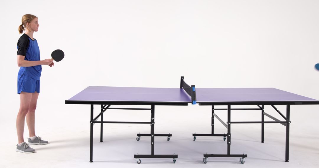 Female Table Tennis Player Ready to Compete on Purple Table in Studio