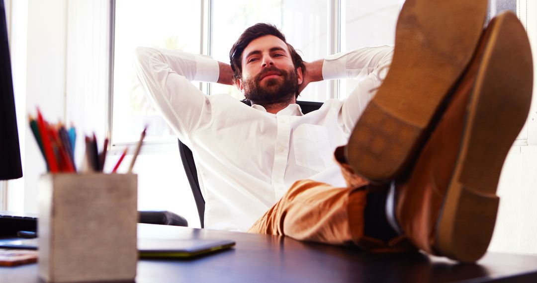 Confident Businessman Relaxing at Desk in Office - Free Images, Stock Photos and Pictures on Pikwizard.com