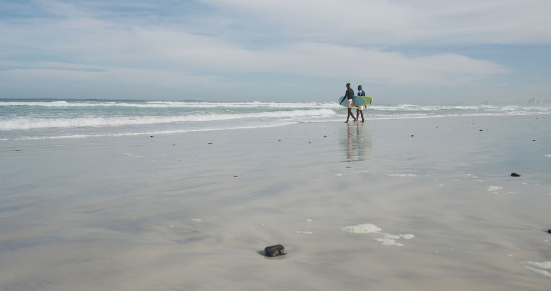 African american father and teenage son walking on a beach holding surfboards and talking - Free Images, Stock Photos and Pictures on Pikwizard.com